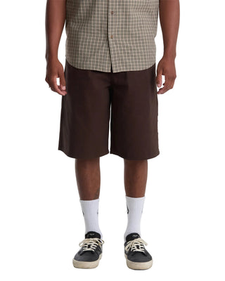 Person wearing a plaid shirt, brown shorts, and black sneakers on a white background