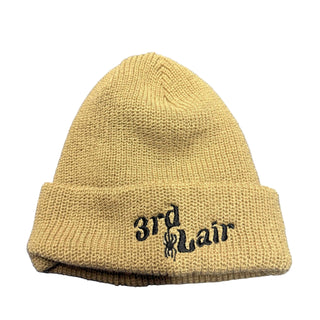 Beige knit beanie with '3rd & Lair' embroidery on a blue tiled background