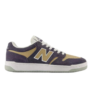 A New Balance sneaker in dark purple suede and tan suede, featuring a white midsole and a white 'N' logo with a purple outline.
